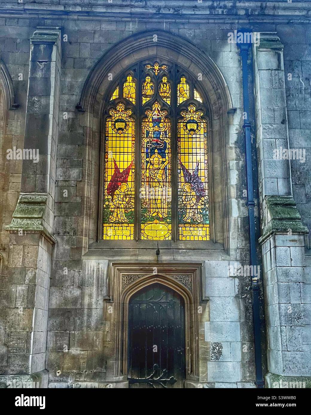 Buntglasfenster und Tür der Kirche des Heiligen Grabes auf Holborn Viaduct, London. Das Fenster wird in der Dämmerung beleuchtet. Denkmalgeschütztes Gebäude der Klasse I. Stockfoto