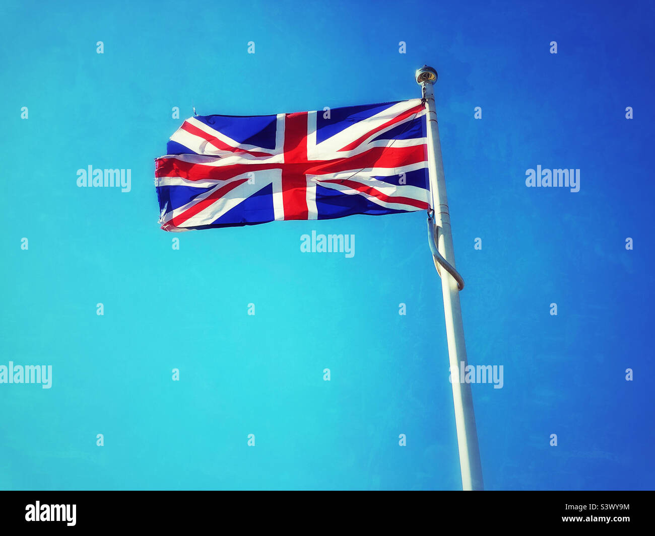 Die Flagge des Vereinigten Königreichs - The Union Jack. Es ist ein warmer sonniger Tag, so dass die Flagge der Union flattert und ihre Farben und ihr Design zeigt. Foto ©️ COLIN HOSKINS. - Smartphone-aufgenommenes Stockfoto