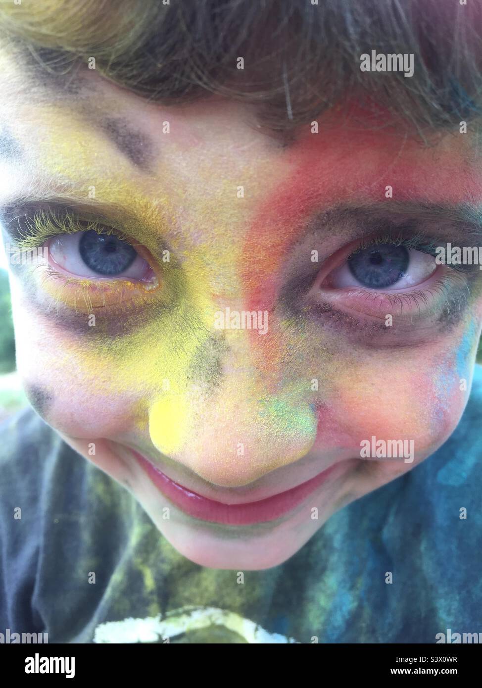 Kindergesicht mit Pulverfarbe bedeckt Nahaufnahme lächelnder Junge - Smartphone-aufgenommenes Stockfoto