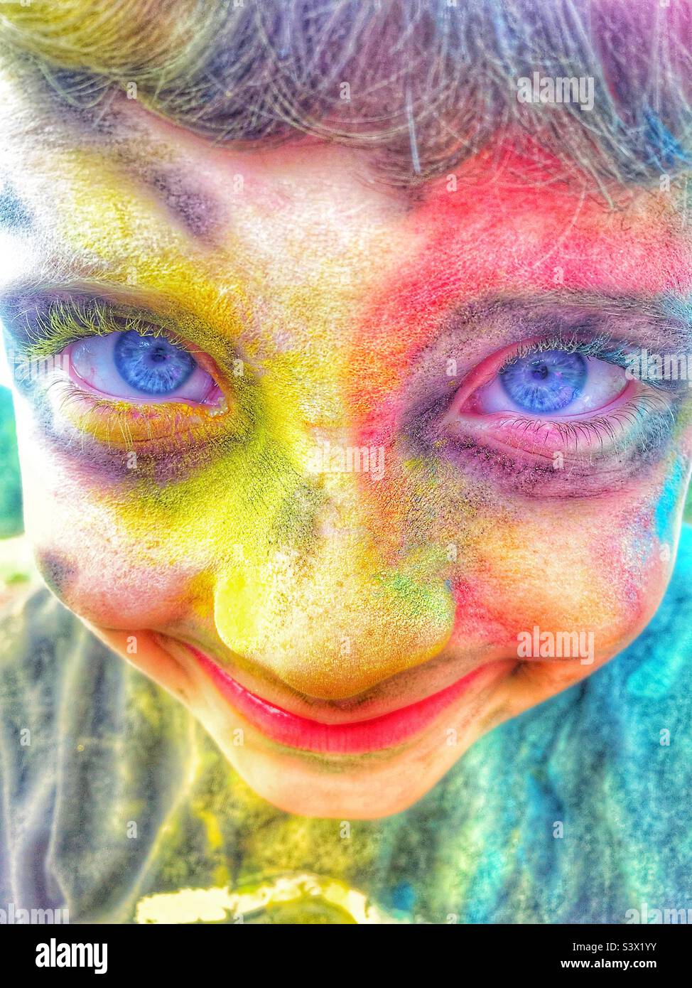 Jungen Gesicht mit leuchtend blauen Augen mit bunten Pulverfarbe bedeckt - Smartphone-aufgenommenes Stockfoto