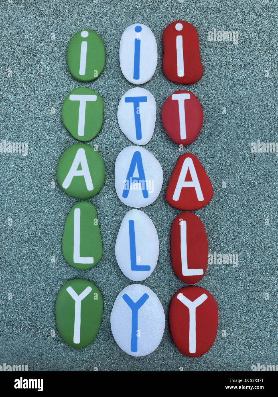 Italien, einzigartiges Souvenir bestehend aus grünen, weißen und roten handbemalten Steinbuchstaben über grünem Sand Stockfoto