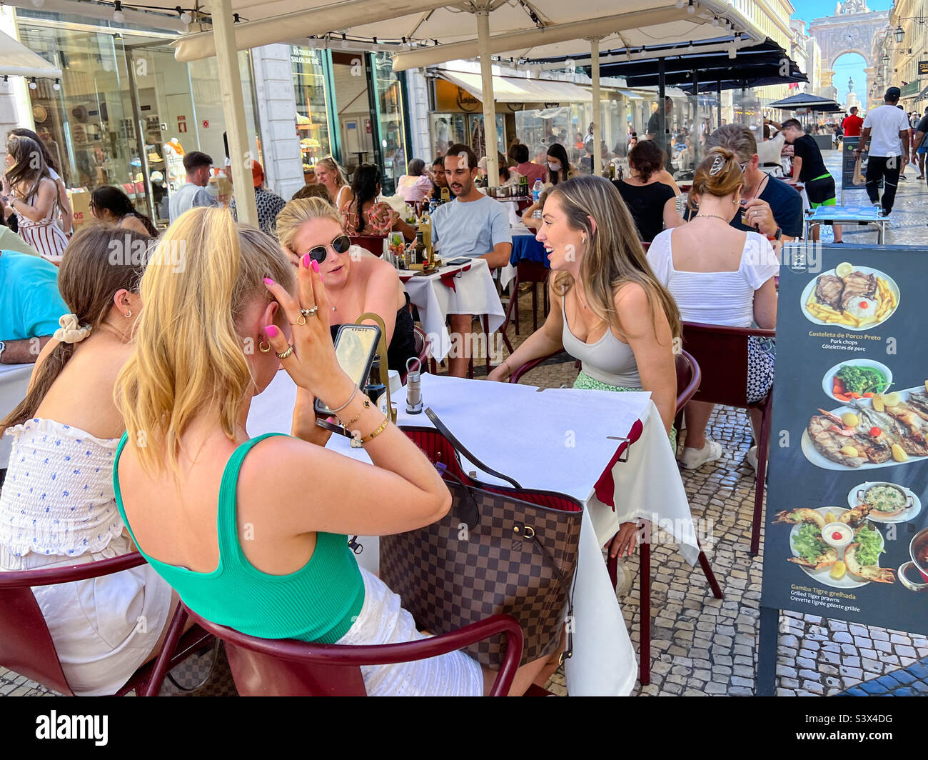 Junge Frau genießt das Mittagessen in der berühmten Rua Agusta Straße in Lissabon Portugal Stockfoto