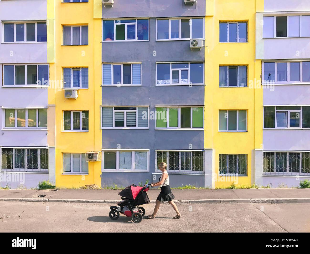 Junge Mutter, die in der Stadt spazieren geht - Smartphone-aufgenommenes Stockfoto
