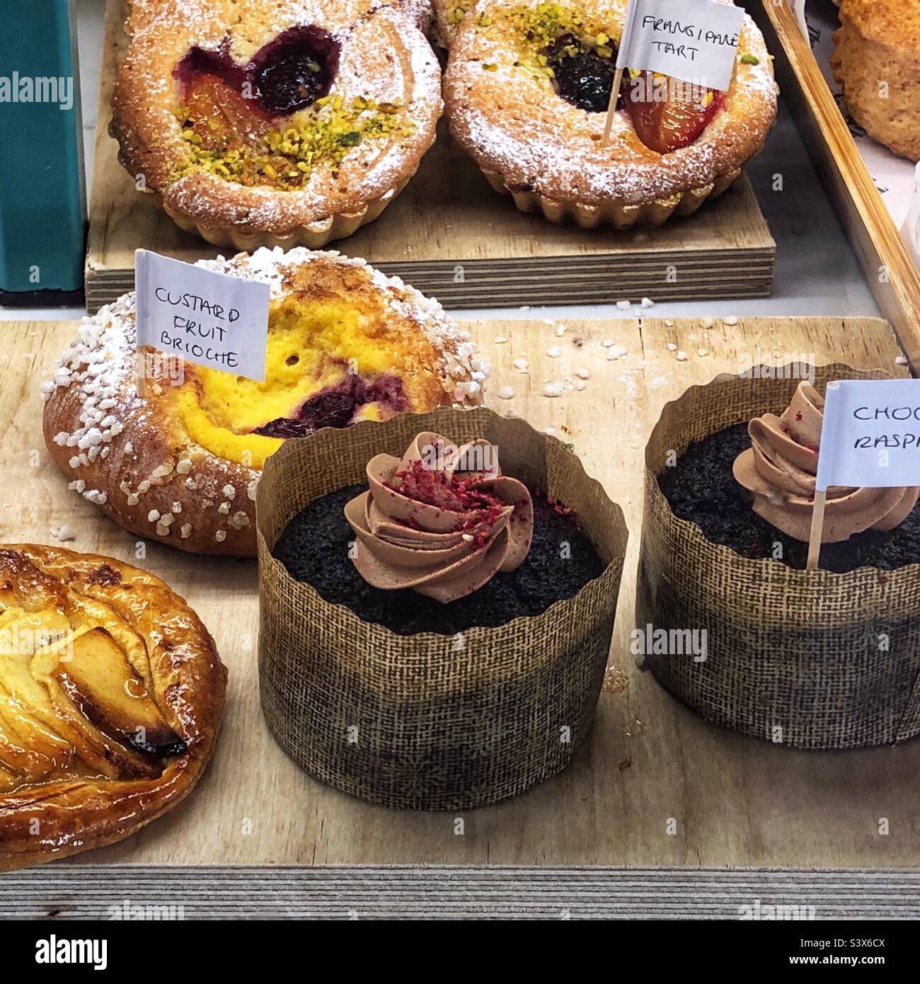 Pudding Fruit Brioche, Frangipane Torte und verschiedene Kuchen im Fenster des Bäckereihandwerks Stockfoto