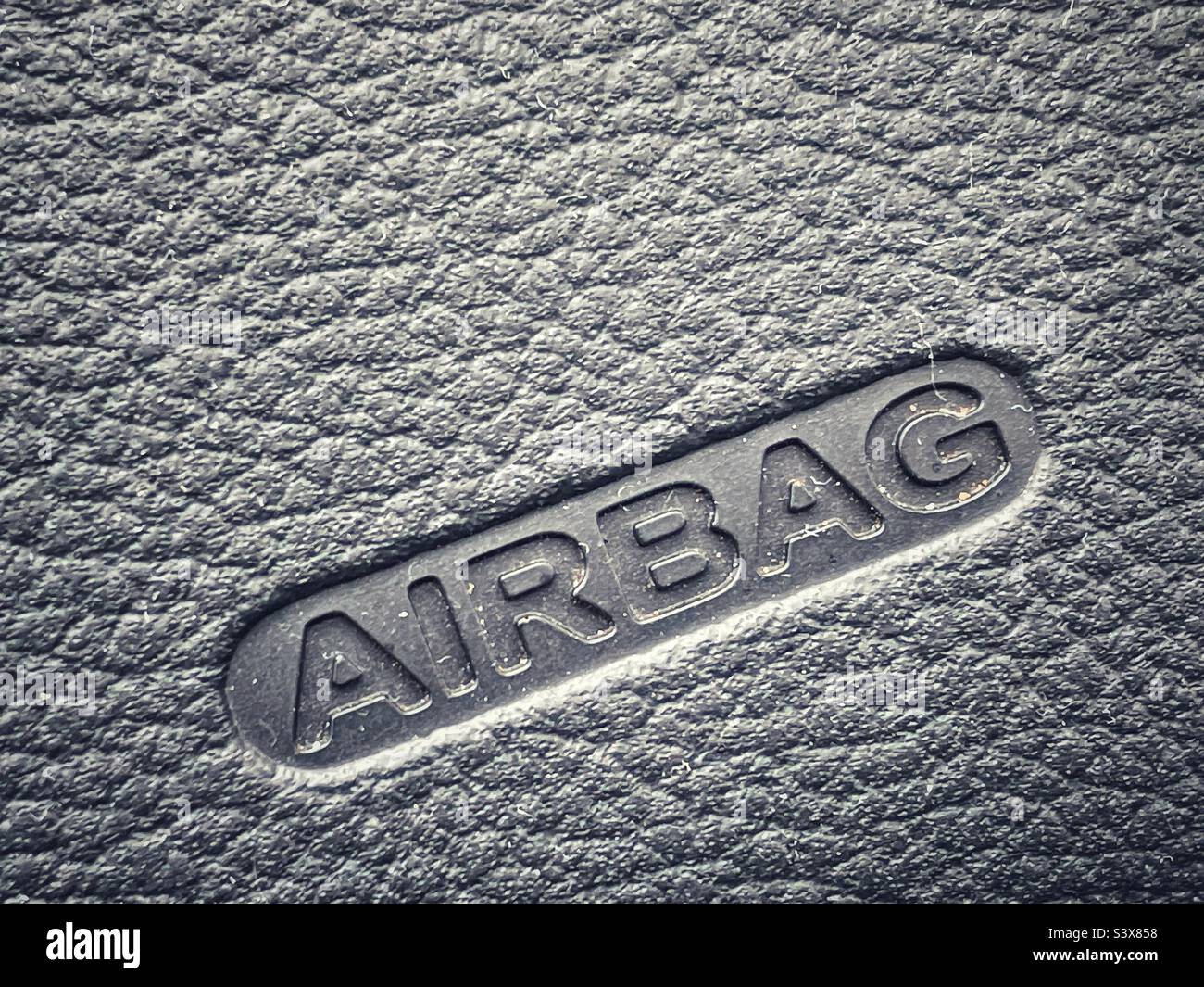 Das Schild für einen Airbag, der in ein texturiertes Vinyl eingestanzt ist. - Smartphone-aufgenommenes Stockfoto