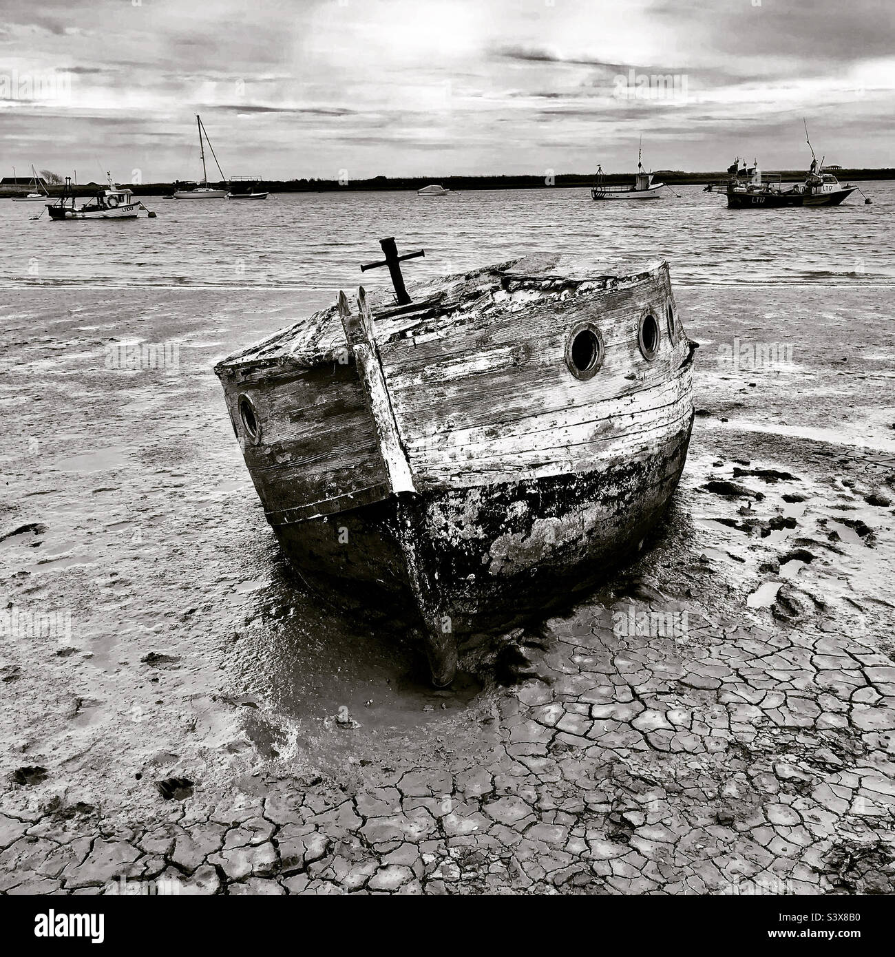 Ein altes verlassene Holzboot sitzt auf den schlammigen Ufern einer Mündung. Stockfoto
