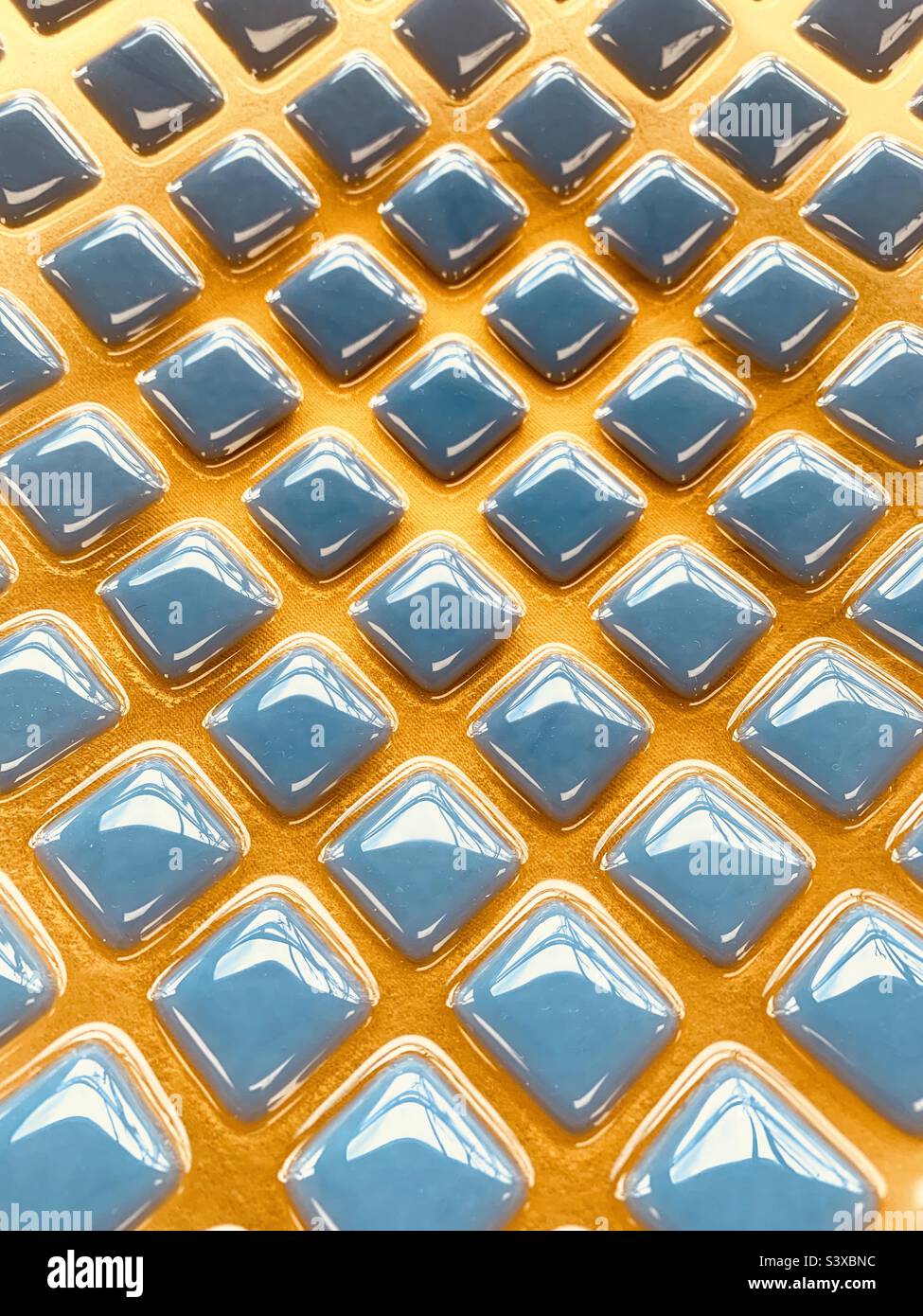 Abstrakte blaue und gelbe Rautenformen auf glänzender Glasstruktur Stockfoto