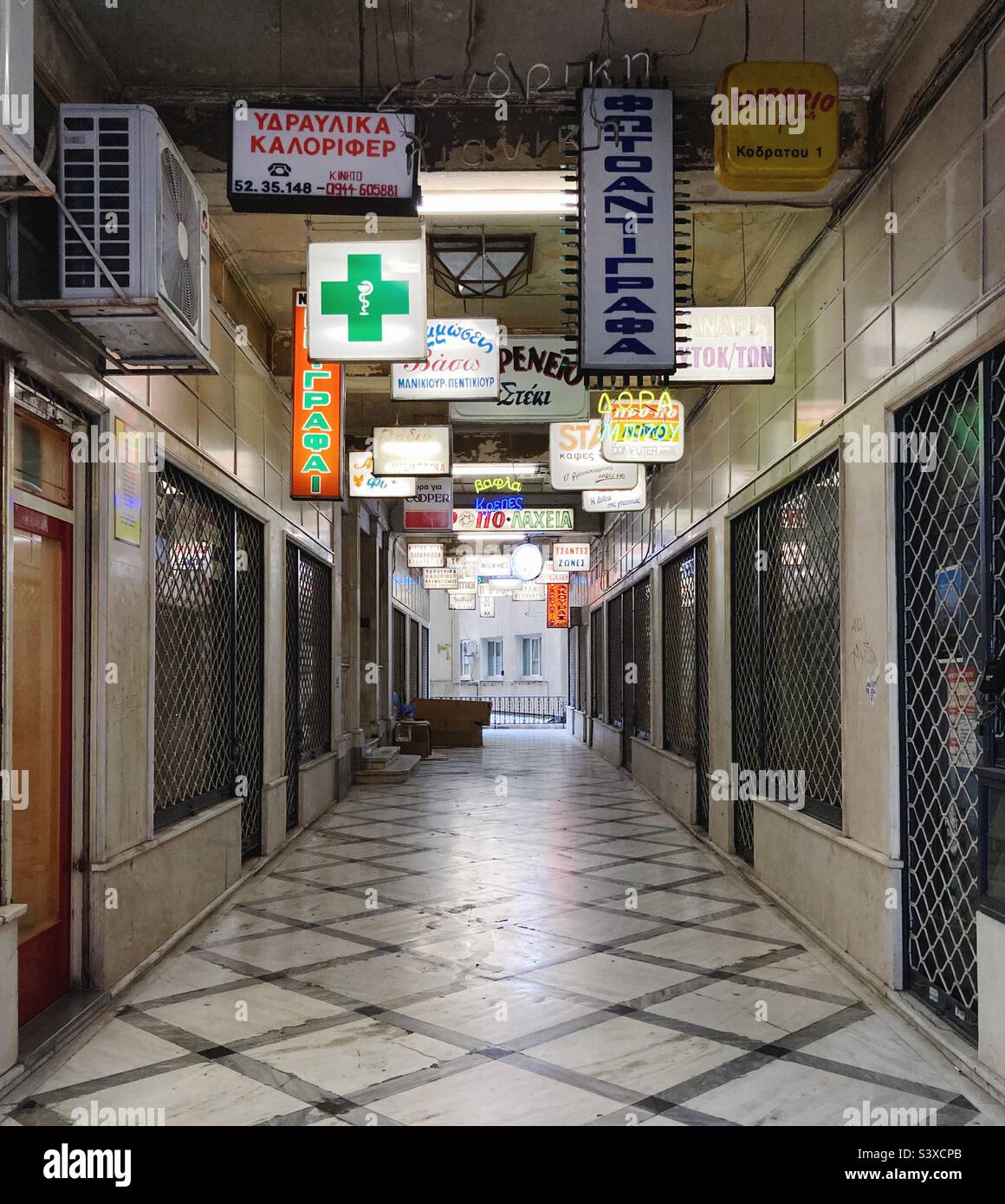 Gasse in Athen, Griechenland, mit beleuchteten Schildern mit den Namen von Geschäften Stockfoto