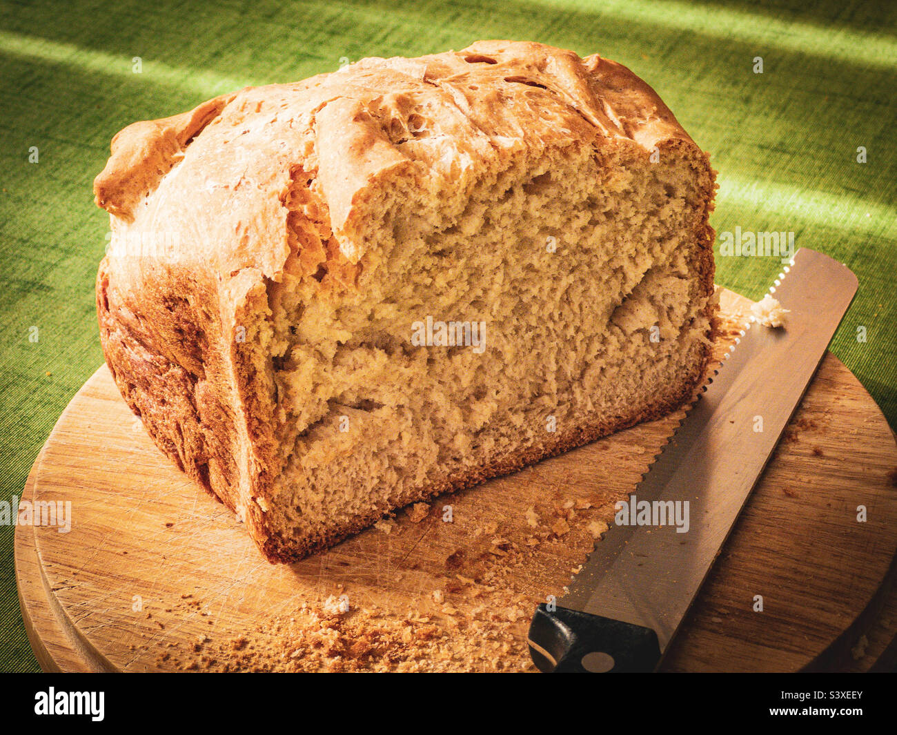 Halber Laib knuspriges Brot auf Holzbrett mit Messer - Smartphone-aufgenommenes Stockfoto