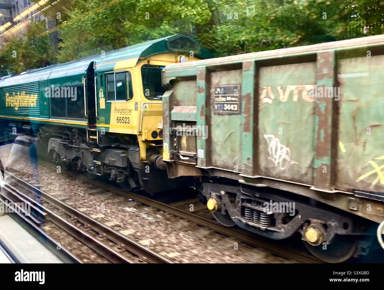 Güterzug, der von einem Passagierzug aus London England in Richtung Clapham Junction Station fährt Stockfoto