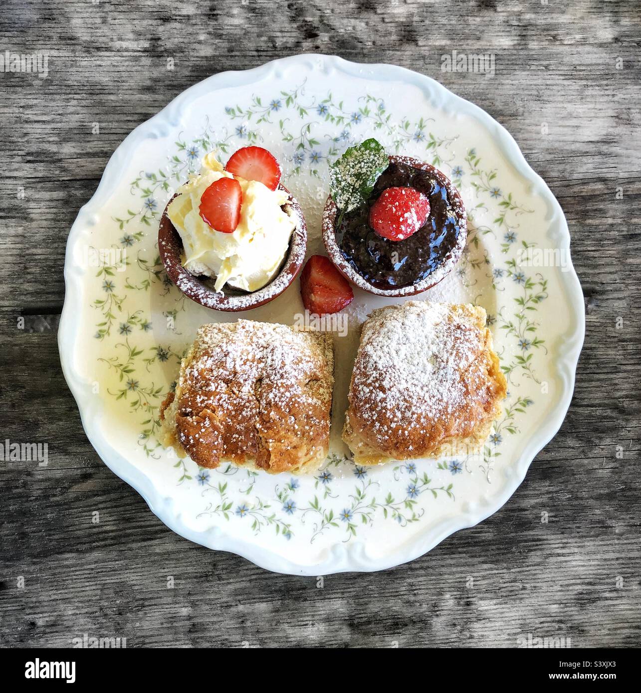 Flaches Essen im Hintergrund eines kornischfarbenen Cremetees mit Scones, Erdbeermarmelade und gerinnter Creme auf einem Vintage-Teller Stockfoto