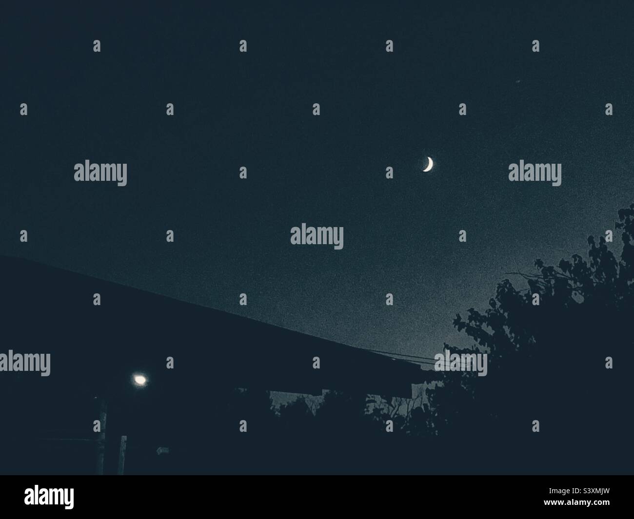 Viertel Mond über Haus mit Veranda Licht Dämmerung. Stockfoto