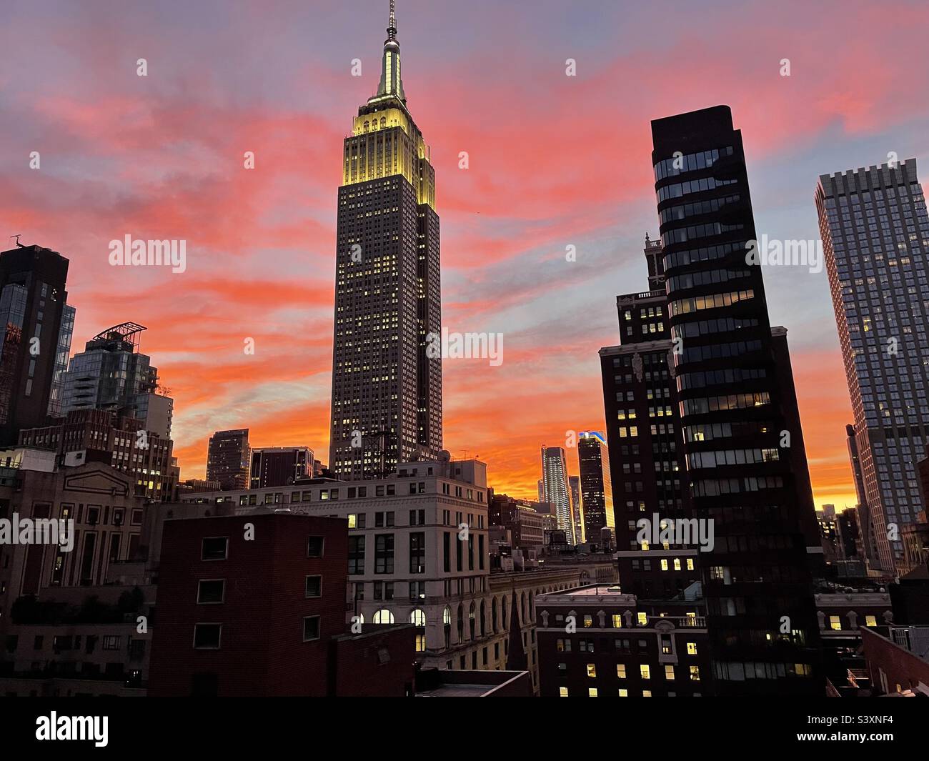 Brillante Sonnenuntergangsfarben, ungefiltert, hinter dem Empire State Building in New York City, USA Stockfoto