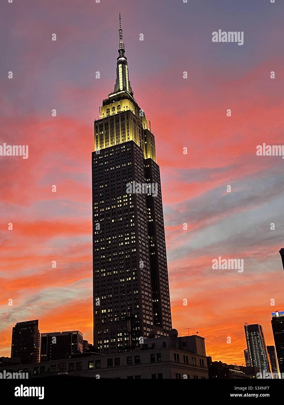 Blick auf die Spitze des Empire State Building bei Sonnenuntergang gegen einen strahlend roten Himmel in New York City, USA Stockfoto