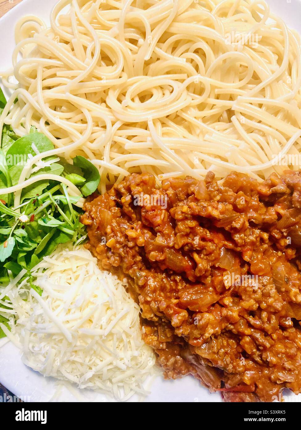 Nahaufnahme von Spaghetti, Bolognaise, geriebenem Käse und gemischten Blättern Stockfoto