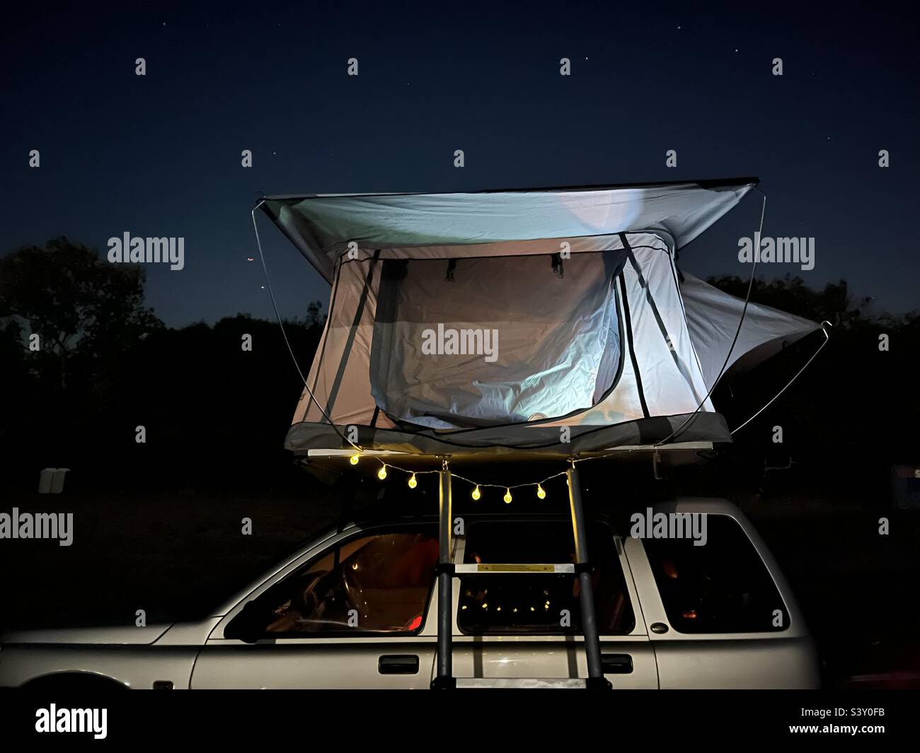 Camping in einem Dachzelt, das an einem Land Rover Freelander auf einem Feld montiert ist Stockfoto