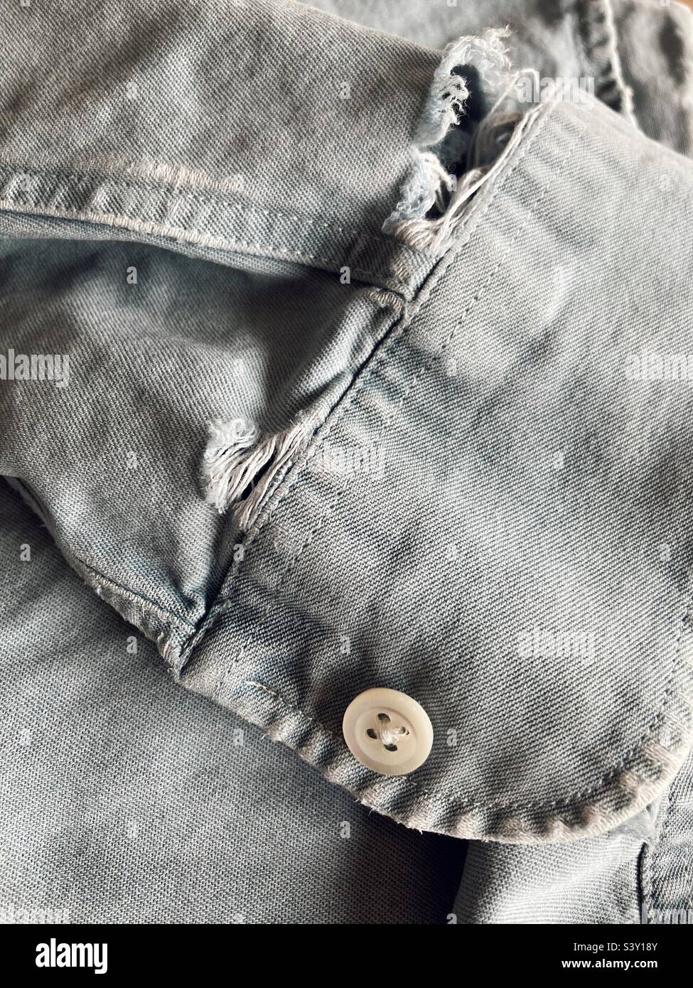 Die ausgefranste Ärmelmanschette eines Jeanshemdes Stockfoto