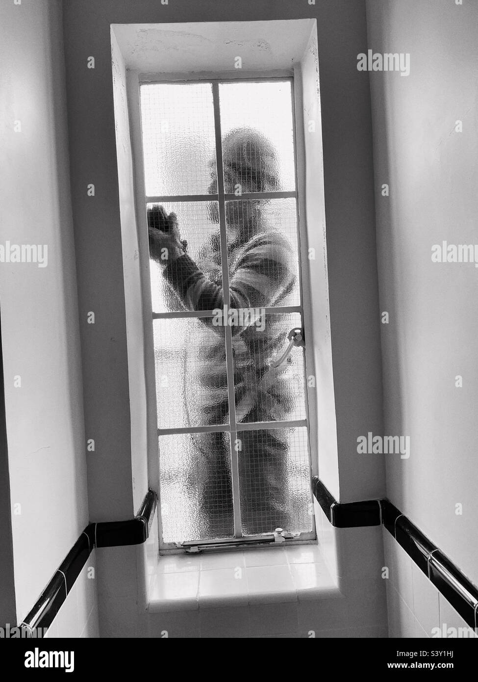 Ein Bauarbeiter, der Ziegelsteine auf einer hängenden Plattform repariert, fügt ein Fensterflügel eines Murray Hill Co-op Hochhauses, 2022, New York City, USA, hinzu - Smartphone-aufgenommenes Stockfoto