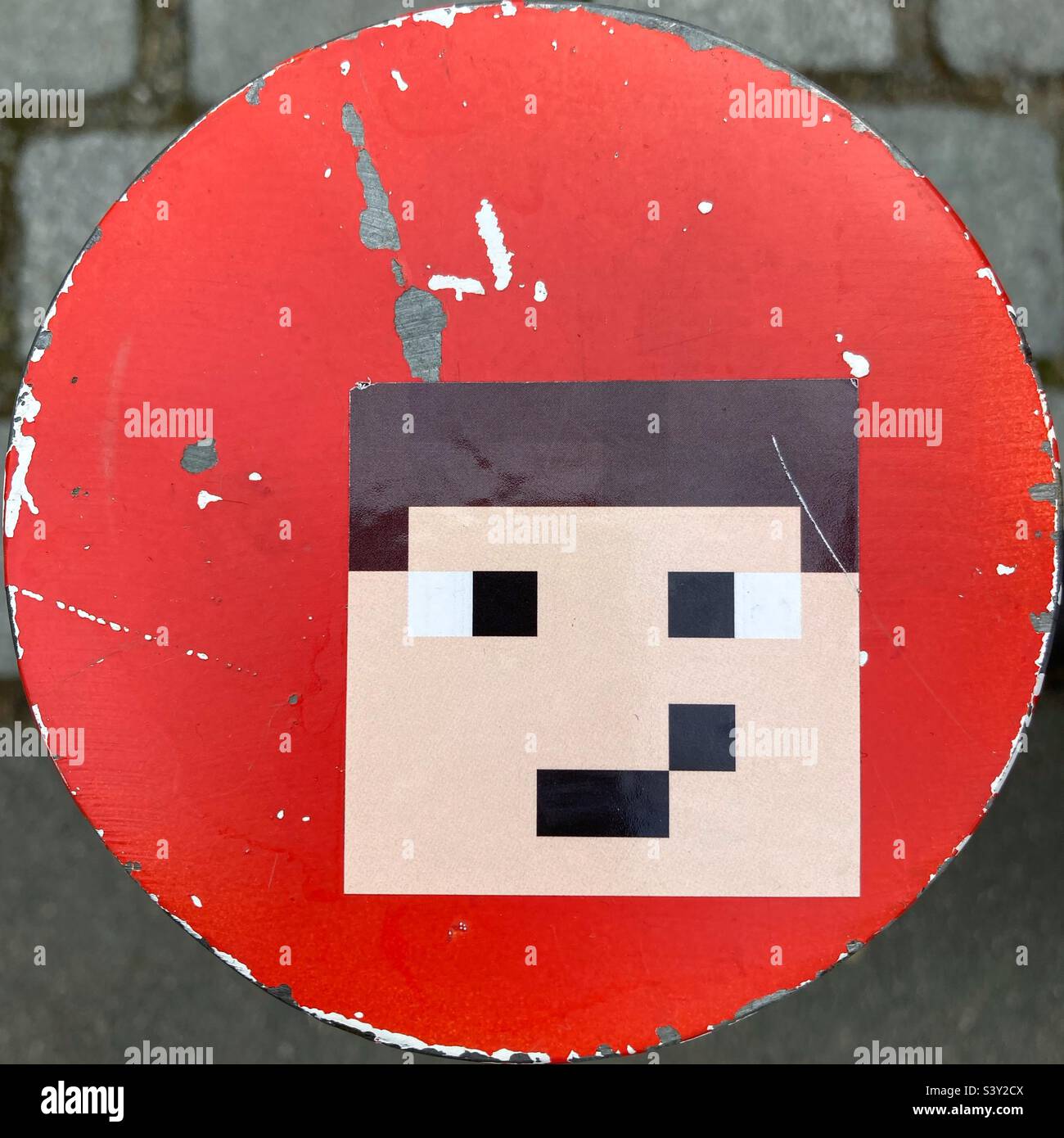 Ein Aufkleber mit einem weinenden männlichen Minecraft-Gesicht auf einer roten runden Oberfläche eines Pollers Stockfoto