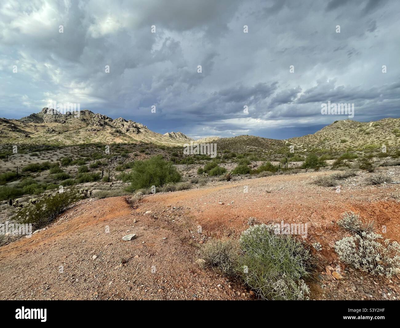 Sturmwolken sammeln sich über dem Piestewa Peak und verträumte Anziehungen, orangene alte Grubenbergwerke im Vordergrund, Phoenix AZ Mountain Preserve Stockfoto