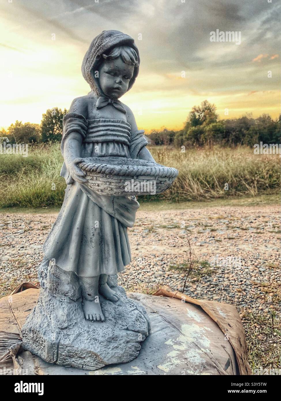 Kleines Mädchen Zement Statue mit Sonnenuntergang im Hintergrund Stockfoto