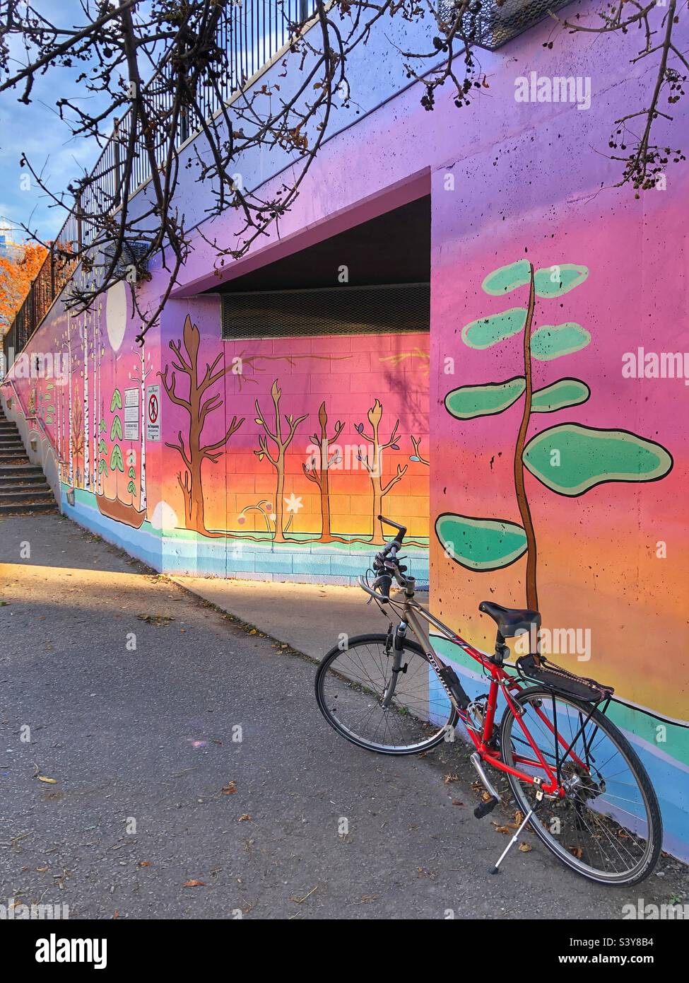 Ein Fahrrad, das vor einem farbenfrohen Wandbild geparkt ist. Stockfoto