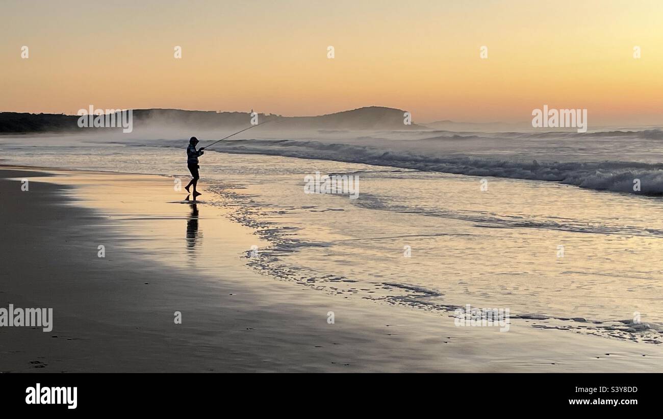 Mann beim Angeln am North Haven Beach, NSW bei Sonnenaufgang. Stockfoto