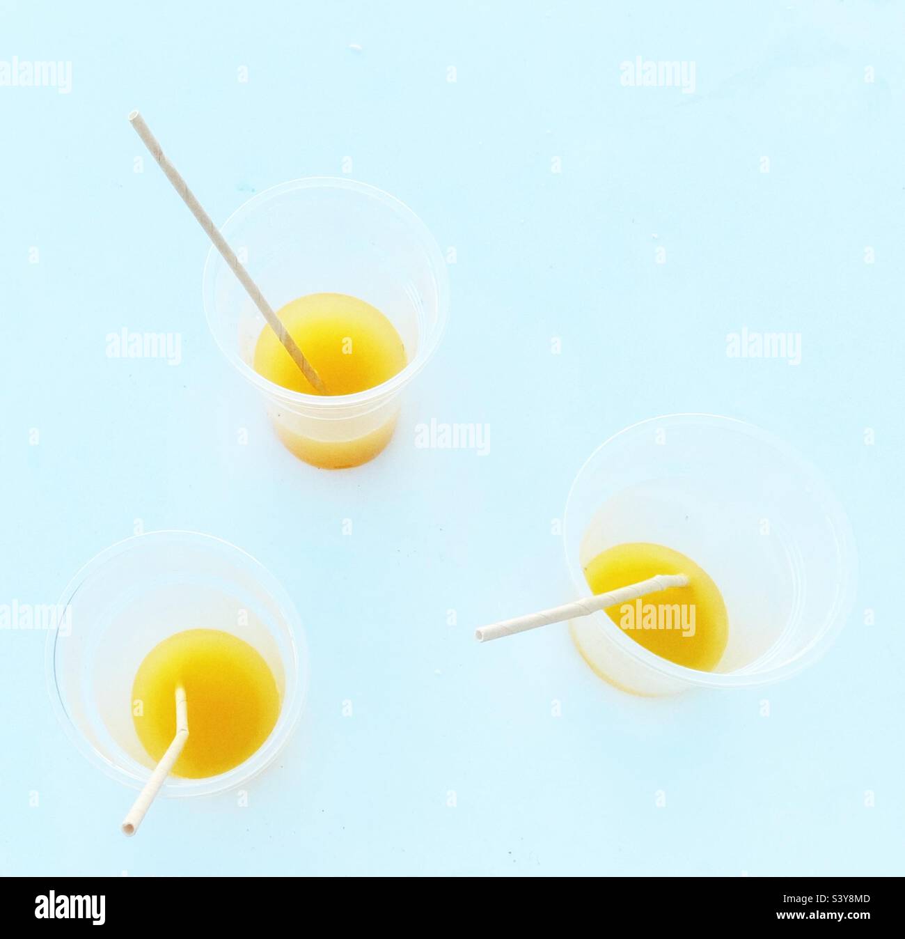 Drei teilweise betrunkene Plastikbecher mit Orangensaft und Trinkhalmen Stockfoto