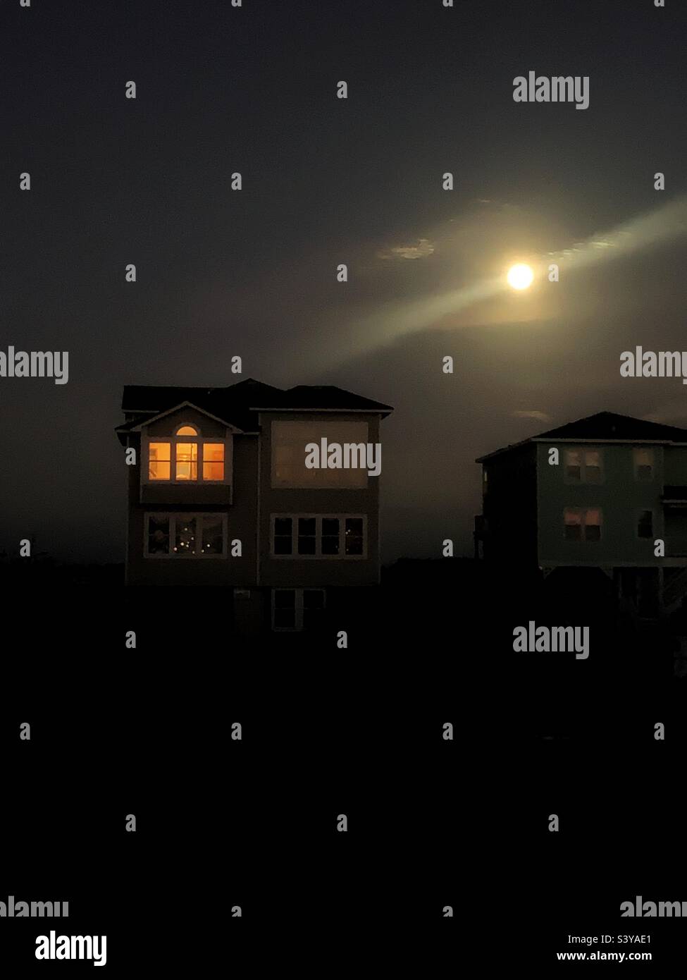 Häuser am Strand gegen den Nachthimmel mit Mond Stockfoto
