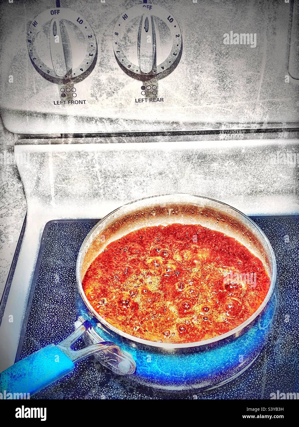 Am Thanksgiving-Tag in einer Küche in Utah, USA, kocht die kochende braune Soße auf einem Kochfeld. Grunge-Effekte aus künstlerischen Gründen digital hinzugefügt. - Smartphone-aufgenommenes Stockfoto