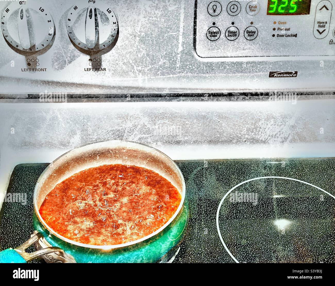 Am Thanksgiving-Tag in einer Küche in Utah, USA, kocht die kochende braune Soße auf einem Kochfeld. Grunge-Effekte aus künstlerischen Gründen digital hinzugefügt. - Smartphone-aufgenommenes Stockfoto