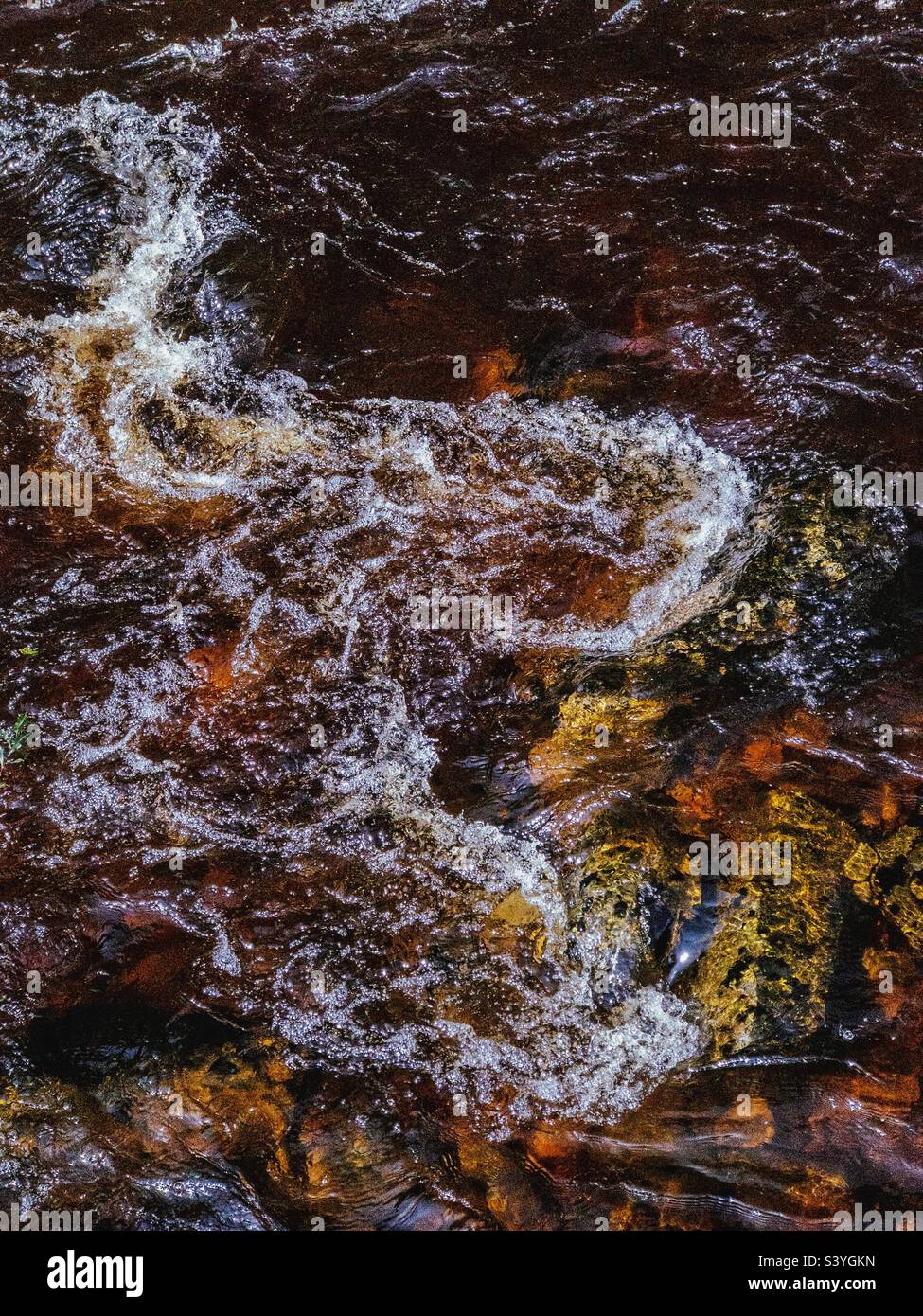Dunkelbraunes Wasser in einem schottischen Fluss. Die braune Farbe kommt vom Torf in den Mooren. Stockfoto