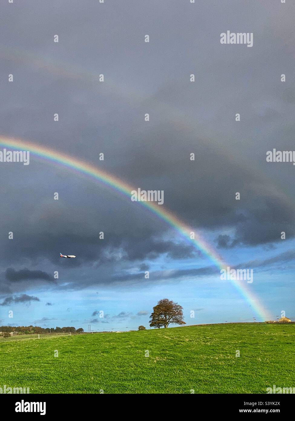 Flugzeug nähert sich Leeds Bradford Flughafen unter einem doppelten Regenbogen auf dem Chevin Otley West Yorkshire Stockfoto