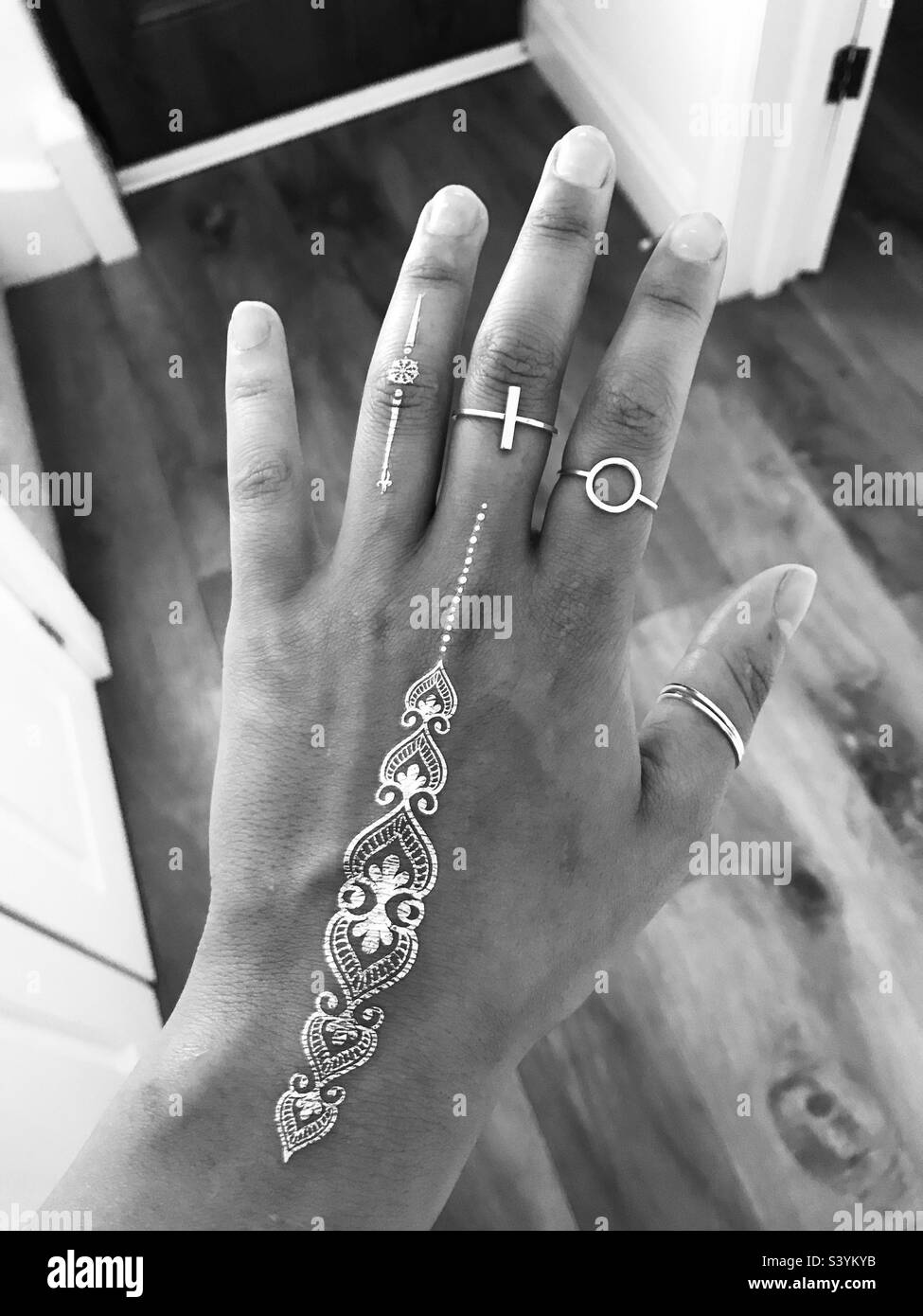 Hand mit Ringen und metallischen temporären Tattoos Stockfoto