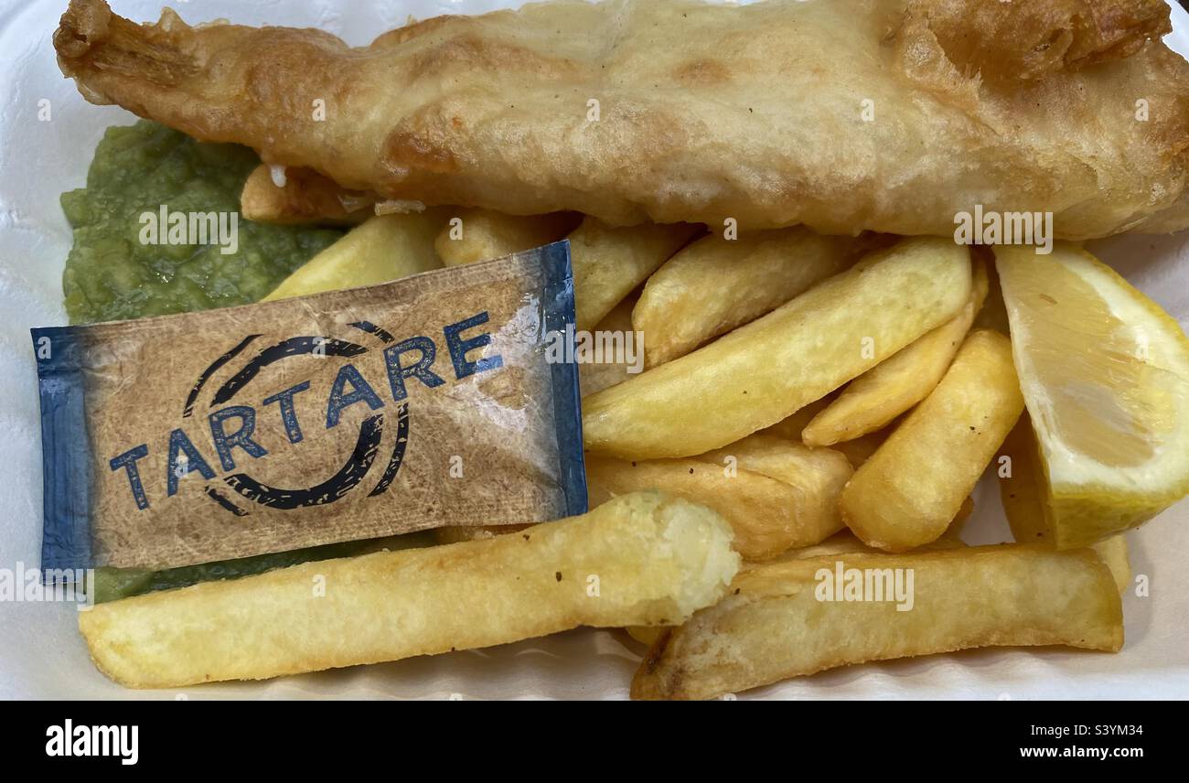 Fischchips und matschige Erbsen mit Tartaresauce und einem Keil Zitrone - Smartphone-aufgenommenes Stockfoto