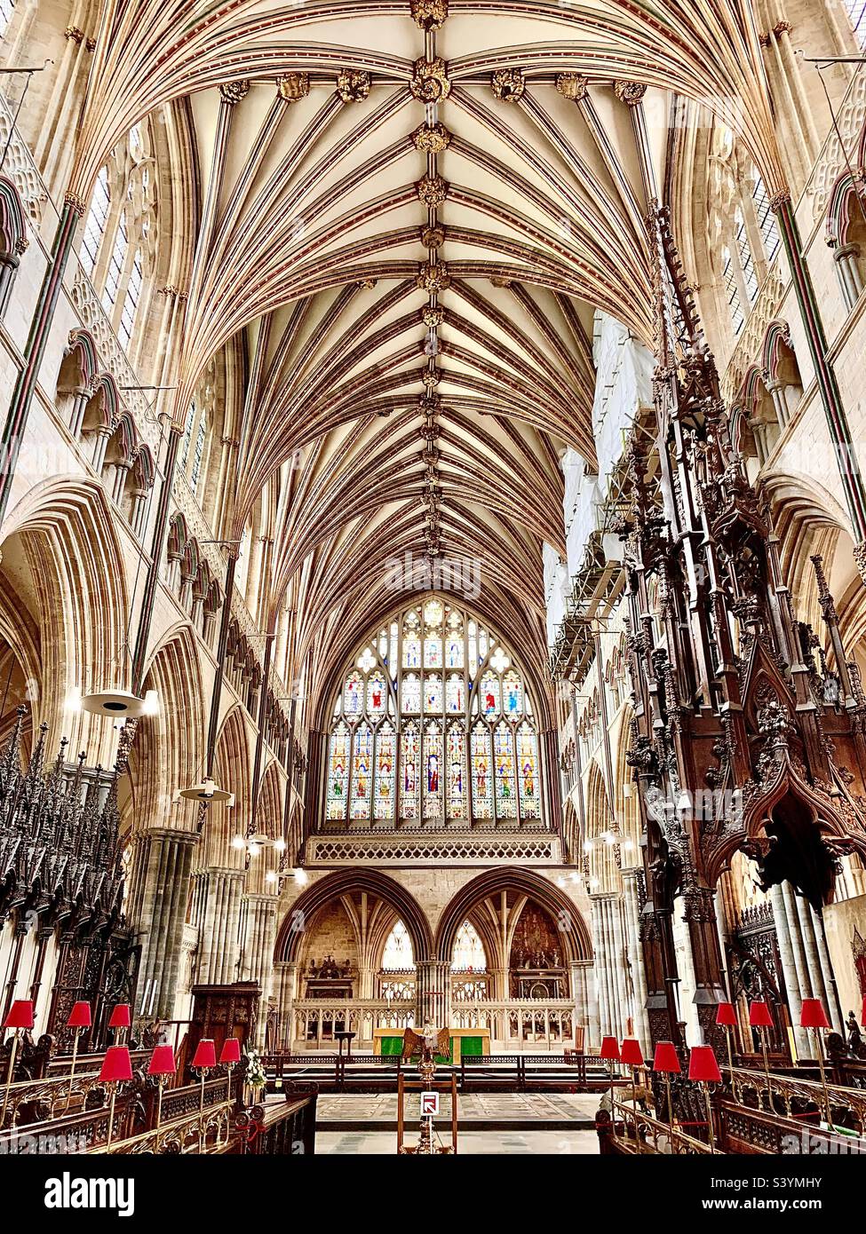 Das Innere der Kathedrale von Exeter, einem prächtigen Gotteshaus für die Kirche von England mit einem prächtigen Kirchenschiff und einer detailgetreuen, architektonisch geschnitzten Decke mit riesigen Buntglasfenstern über dem Altar Stockfoto