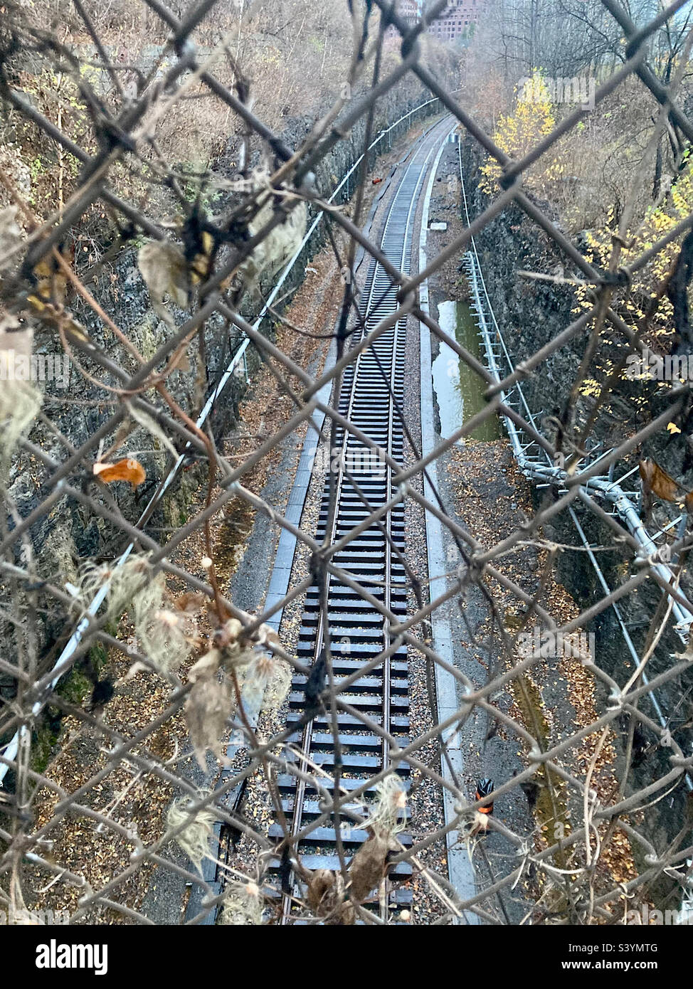Stadtbahngleise, die durch einen Kettengliederzaun gesehen werden. Stockfoto