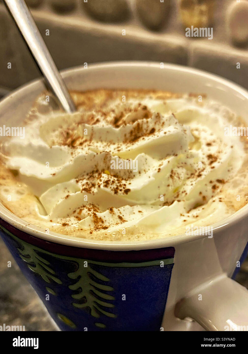 Becher mit Löffel und Schlagsahne mit Zimt Stockfoto