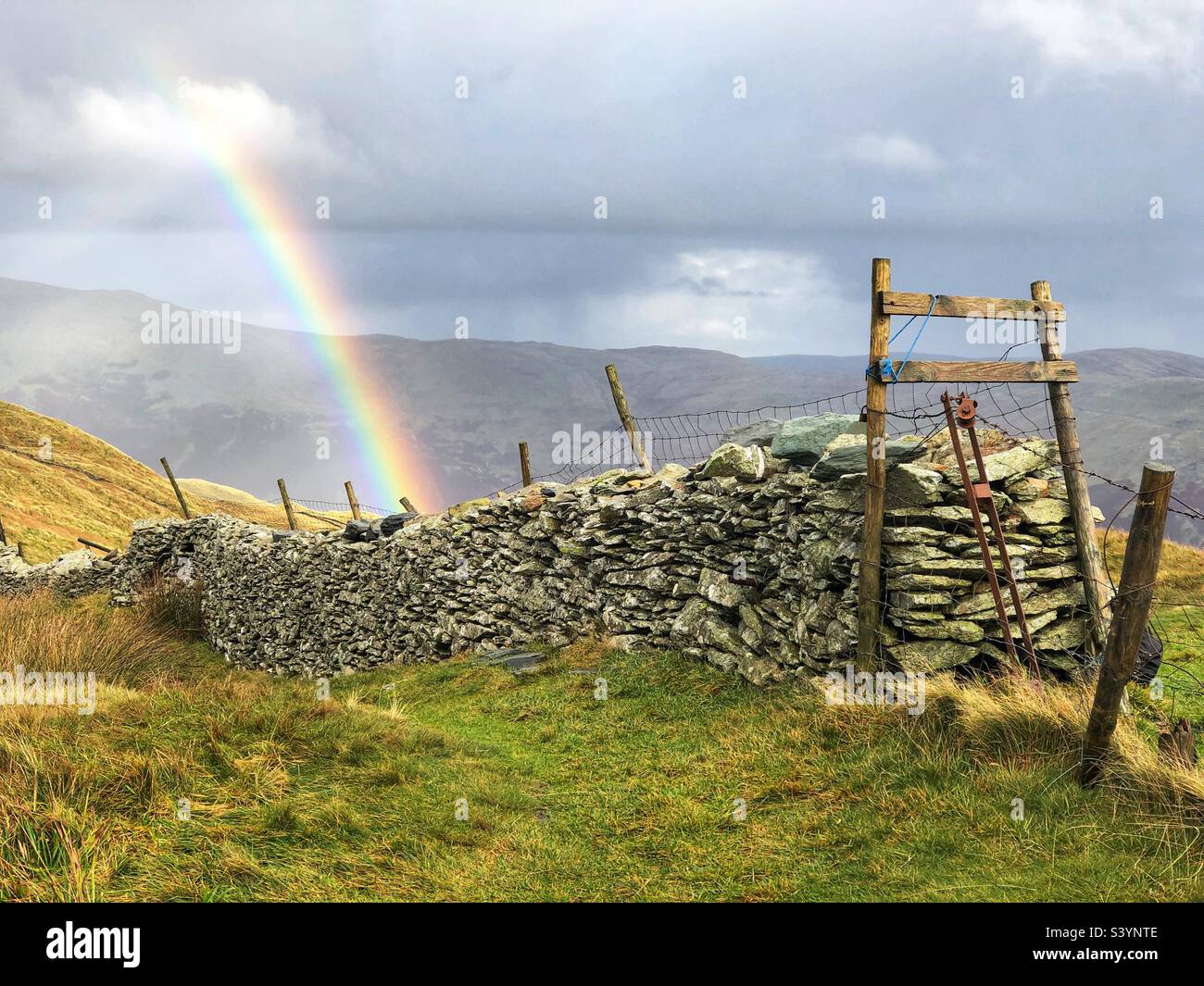 Blick vom Gipfel des Wansfell Pike mit Regenbogen, Steindeiche und Zaun, Ambleside Lake District - Smartphone-aufgenommenes Stockfoto
