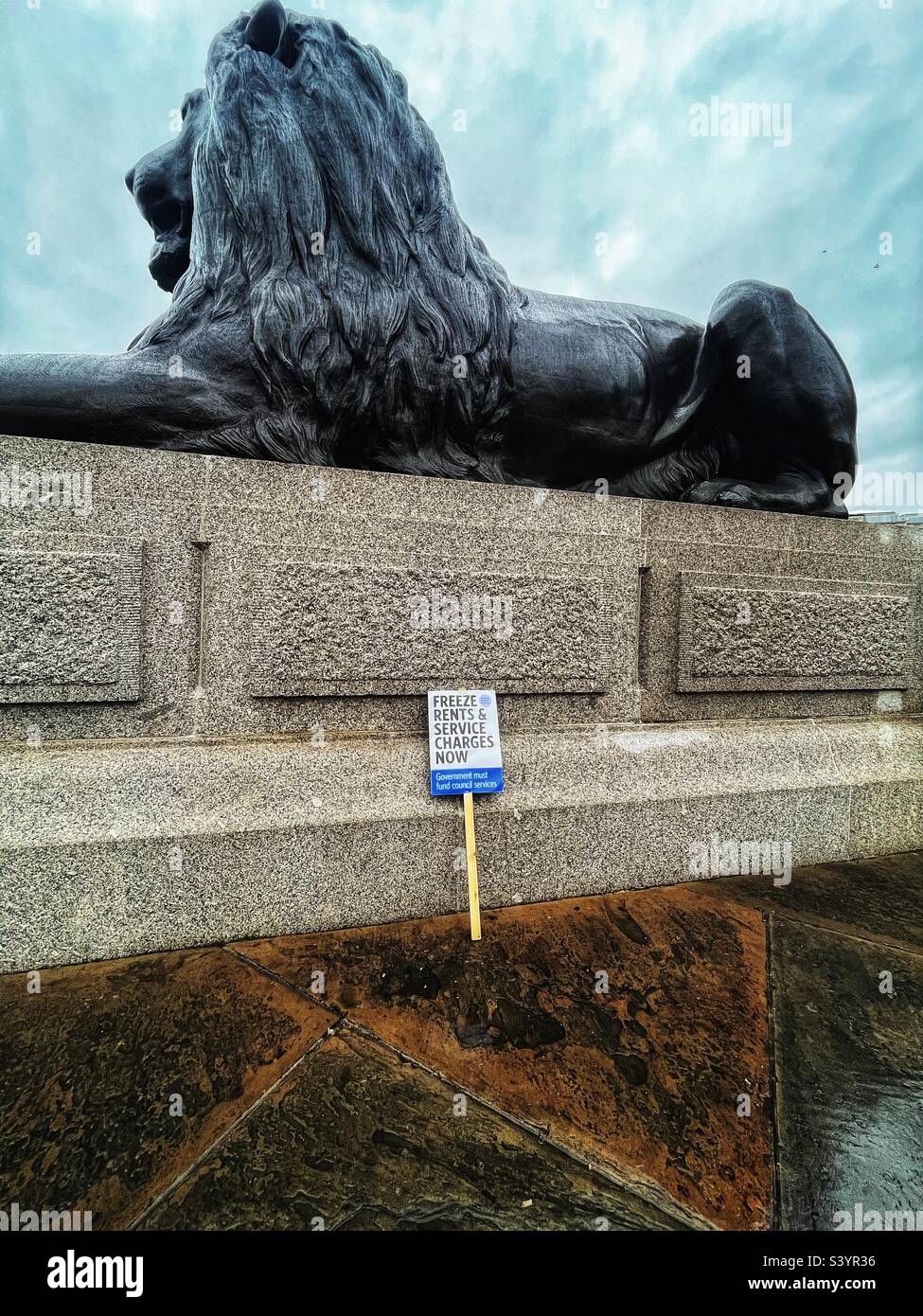 Das von der Löwenstatue am Trafalgar Square in London weggeworfene Plakat besagt: „Einfrieren von Mieten und Servicegebühren jetzt“ folgt der Demonstration gegen die Regierungspläne für Sparmaßnahmen im Vereinigten Königreich im November 22 Stockfoto