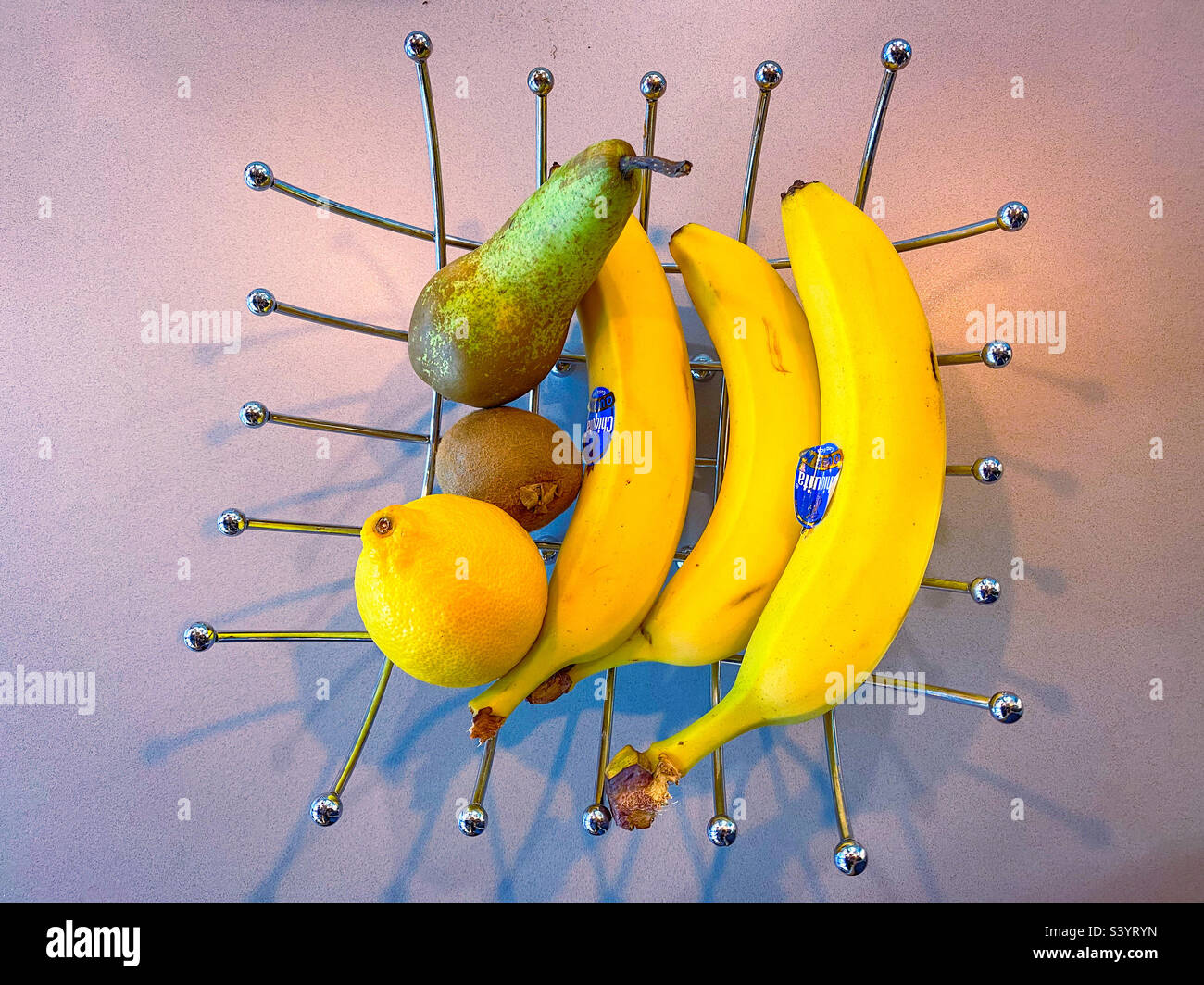 Obst in einer schicken, dekorativen Obstschale auf einer Arbeitsplatte. Stockfoto