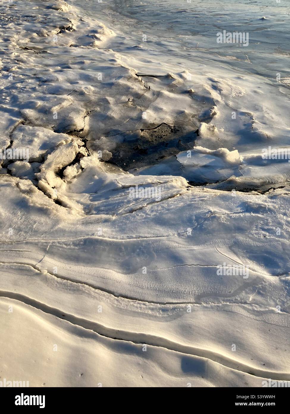 Gefrorener Hafen als Sonnenuntergänge während eines Connecticut Winters. Die Aufnahme zeigt Eisschichten mit verkrustetem Schnee auf der Oberseite. - Smartphone-aufgenommenes Stockfoto