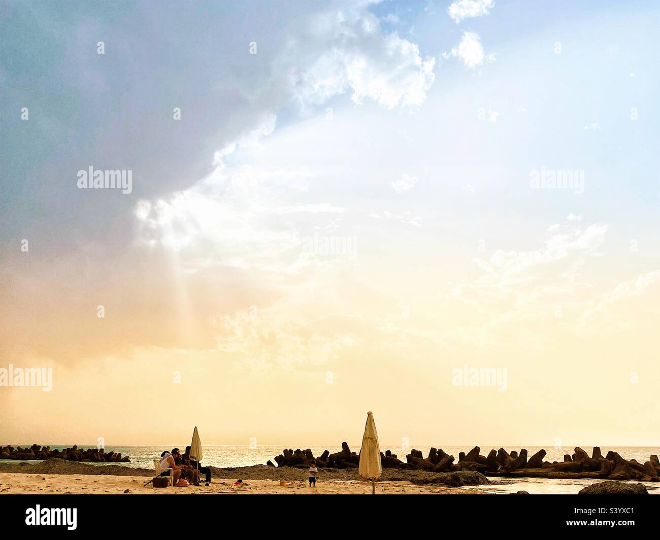 Die Sonne blickt durch die Wolken am Strand - Smartphone-aufgenommenes Stockfoto