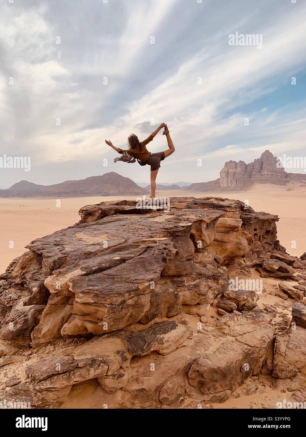 Eine Frau, die Yoga-Pose auf einem Hügel in der nördlichen Wüste macht, wadi Rum - Smartphone-aufgenommenes Stockfoto