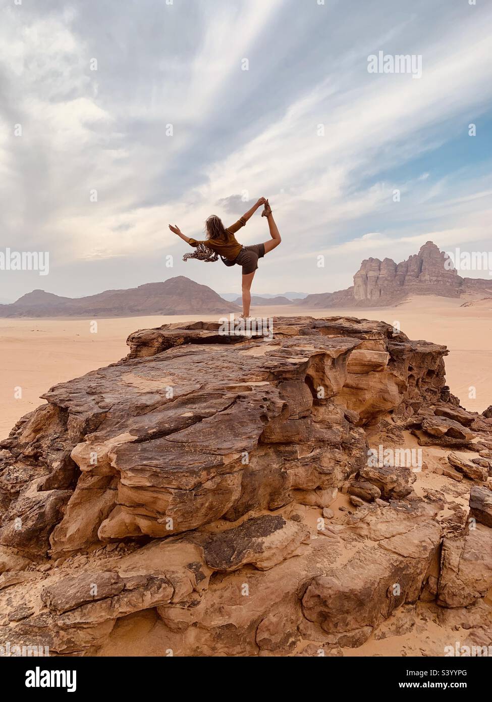 Eine Frau, die Yoga-Pose auf einem Hügel in der nördlichen Wüste macht, wadi Rum Stockfoto