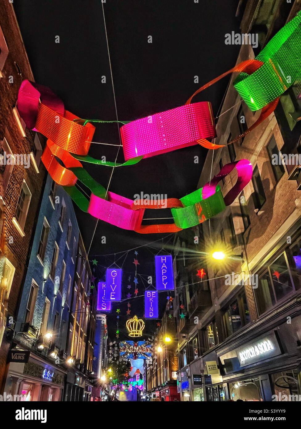 Weihnachtslichter in Form einer riesigen Papierkette auf der schmalen Soho Street in London, die das Nachtleben und den Stadtteil für festliche Feierlichkeiten fördern - Beleuchtung und Farbe in den Wintermonaten Stockfoto