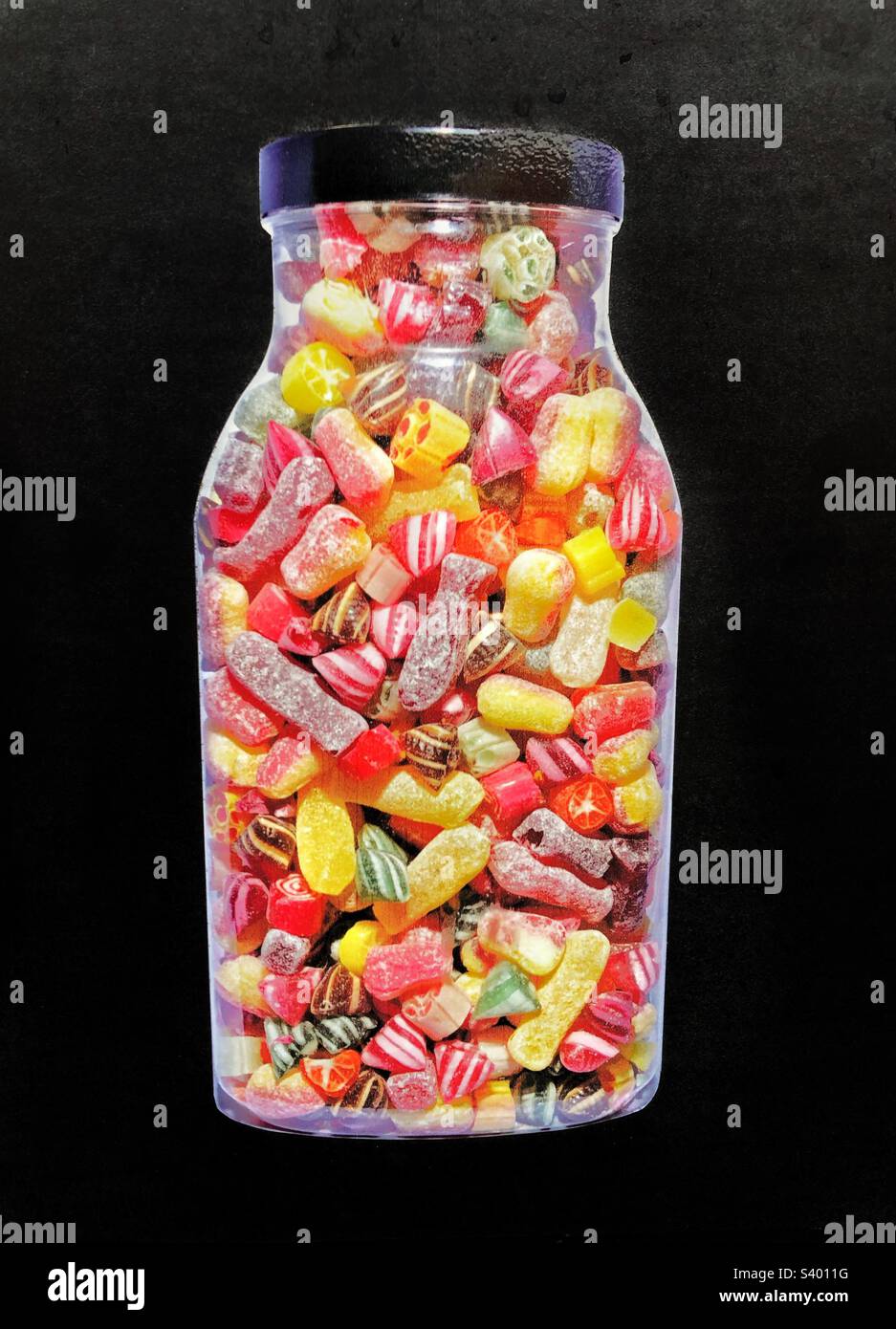 Ein großes Glas mit traditionellen und bunten gekochten Süßigkeiten oder Süßigkeiten auf schwarzem Hintergrund Stockfoto