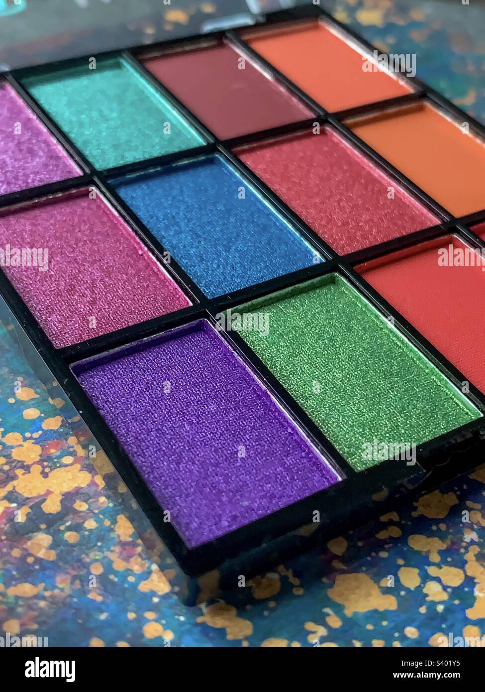 Eine lebhafte Palette an farbenfrohen Augenwiesen und Lipgloss vor einem gemusterten Hintergrund Stockfoto