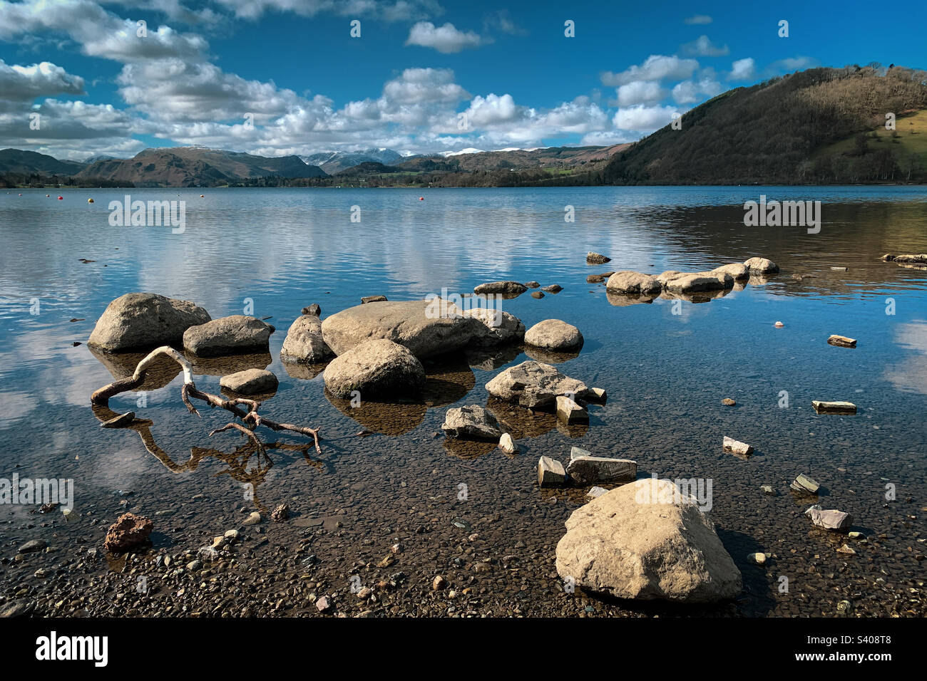 Blick über Ullswater zu einer Schneesprengung auf den Hügeln an einem frischen Frühlingstag in der Nähe von Pooley Bridge, Cumbria, Großbritannien. Ein Mobiltelefon-Foto mit Post Processing auf einem Telefon oder Tablet. Stockfoto