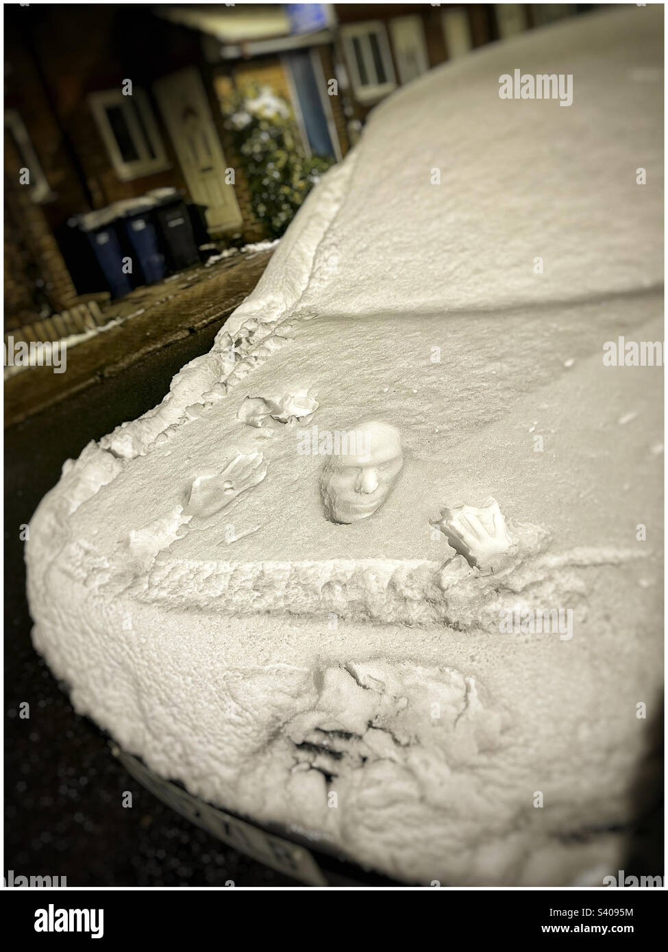 Optische Täuschung von Gesicht im Schnee auf der Motorhaube eines Autos, East Finchley. - Smartphone-aufgenommenes Stockfoto